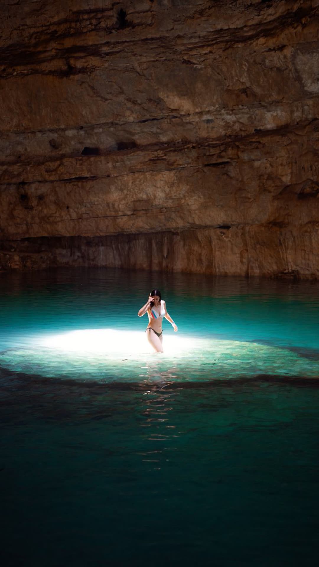 Nadadora en un cenote iluminado por luz natural en Tulum