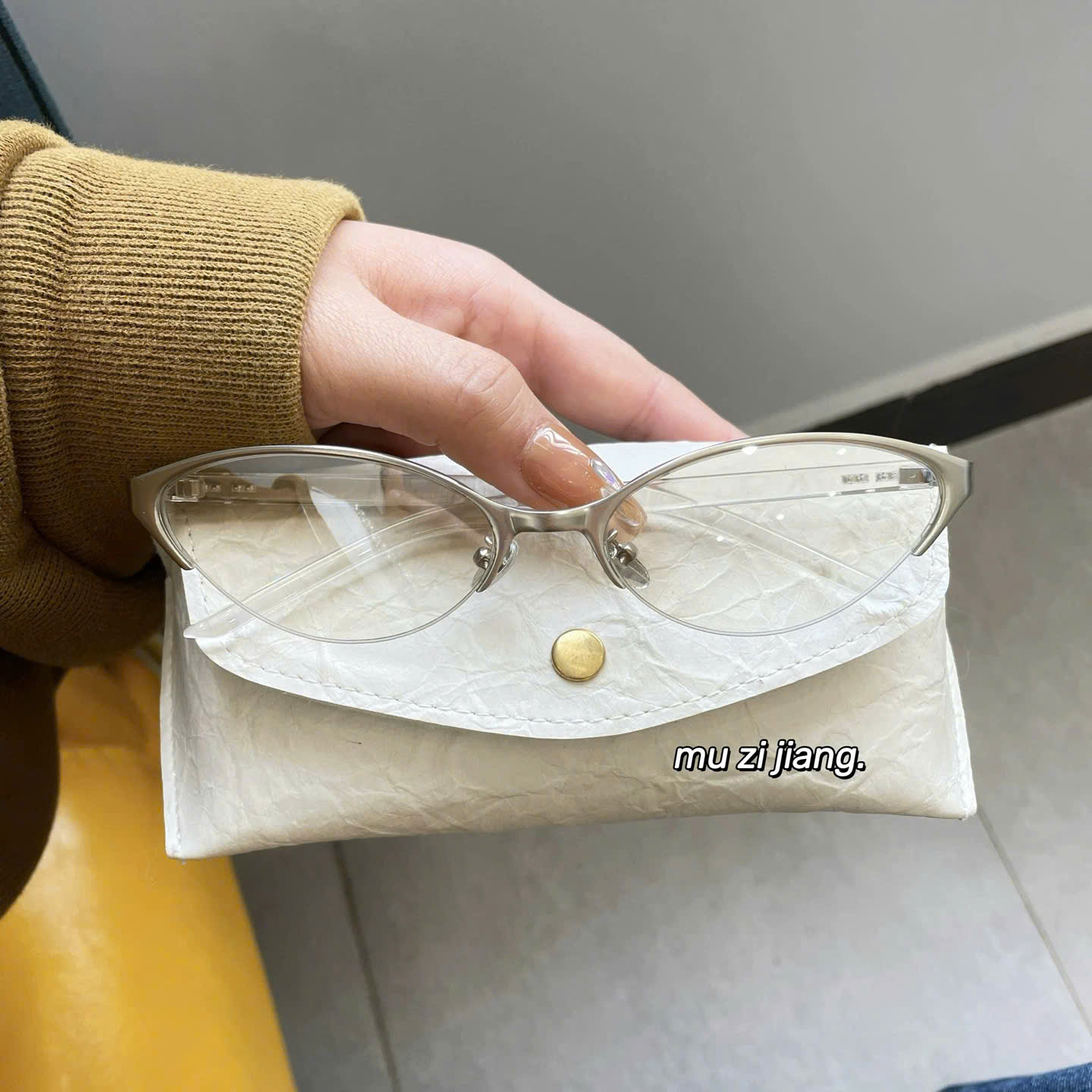 Mắt kính viền bạc gọng nhựa trong suốt.