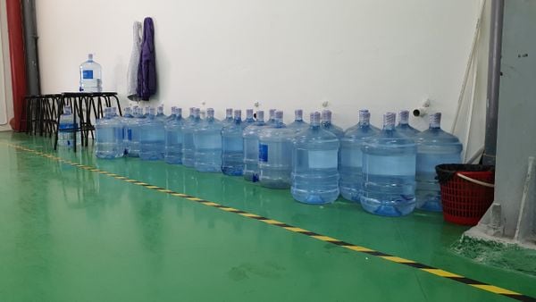 Hàng bình nước 19 lít xếp dọc chân tường nơi làm việc