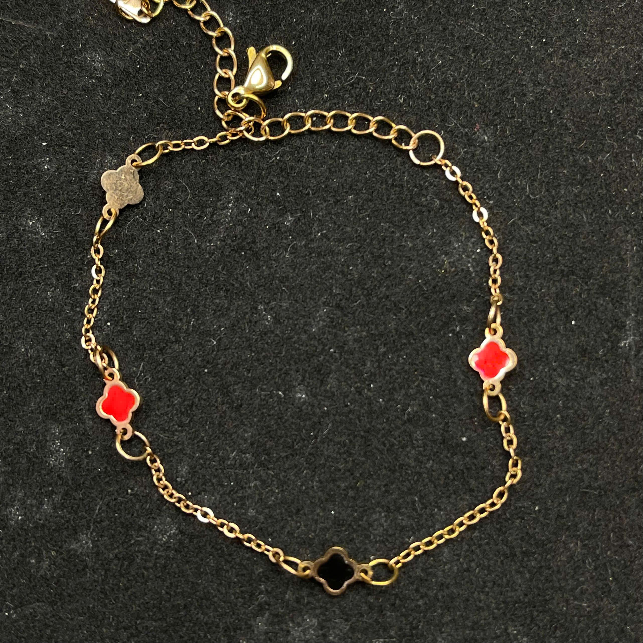 vòng tay titan màu vàng charm hoa bốn cánh đỏ trắng đen.