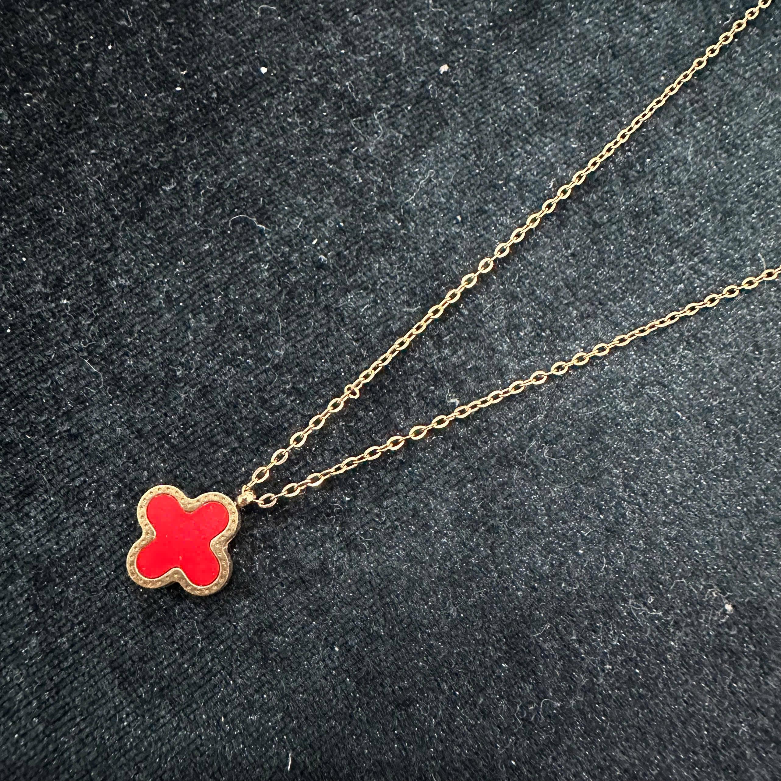vòng cổ titan màu vàng charm hoa bốn cánh đỏ.