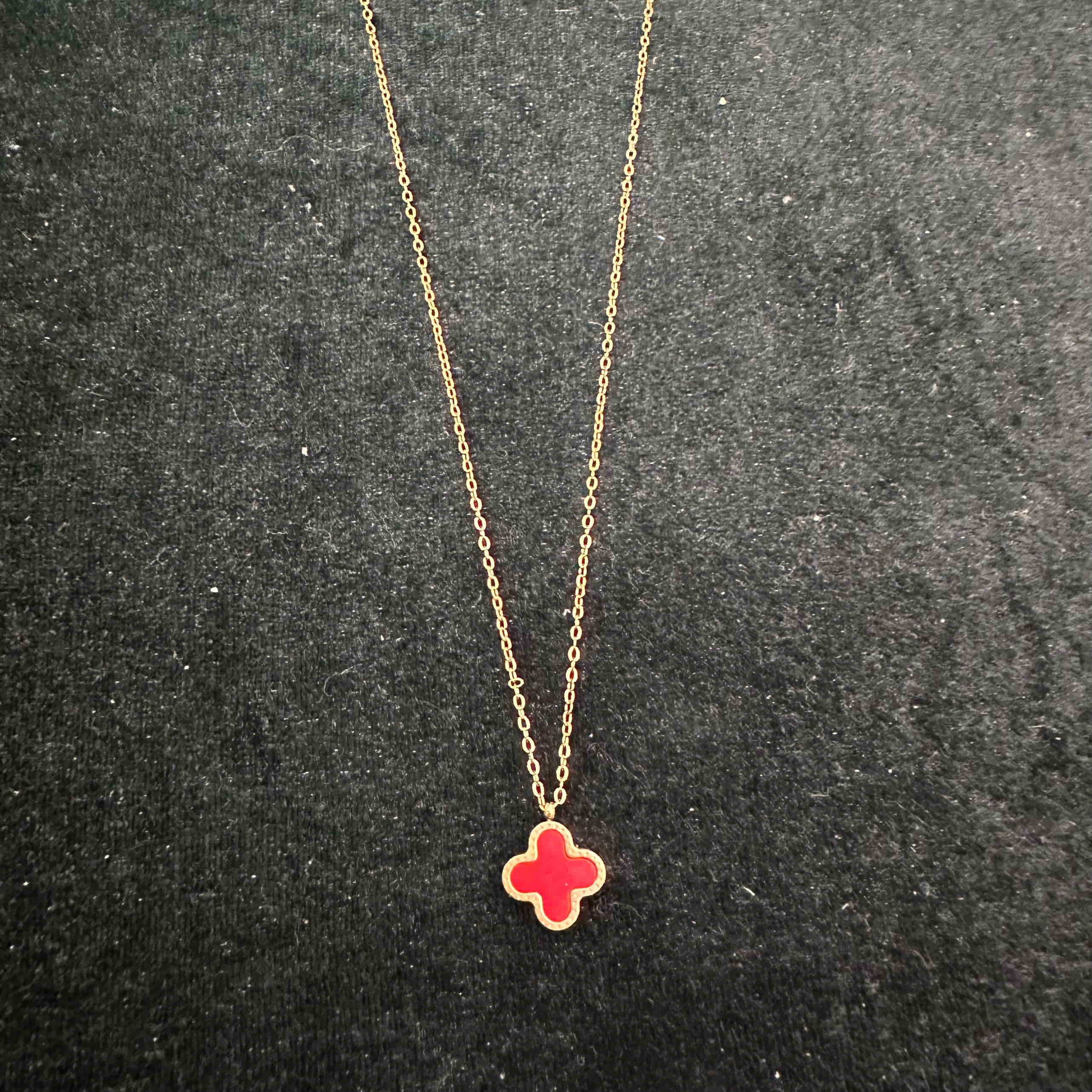 vòng cổ titan màu vàng charm hoa bốn cánh đỏ.