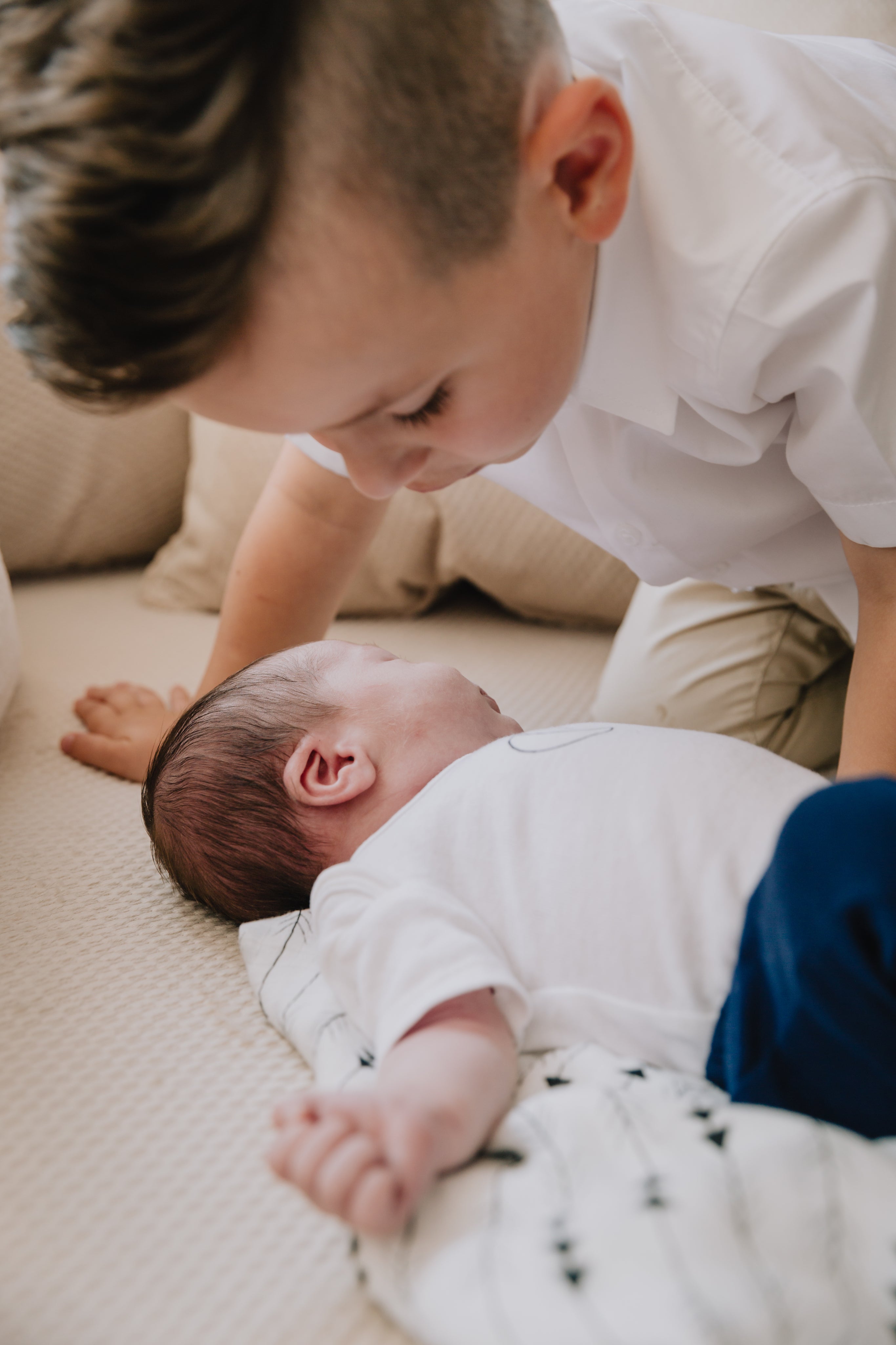 baby-lays-on-a-blanket-with-a-child-saying-hello